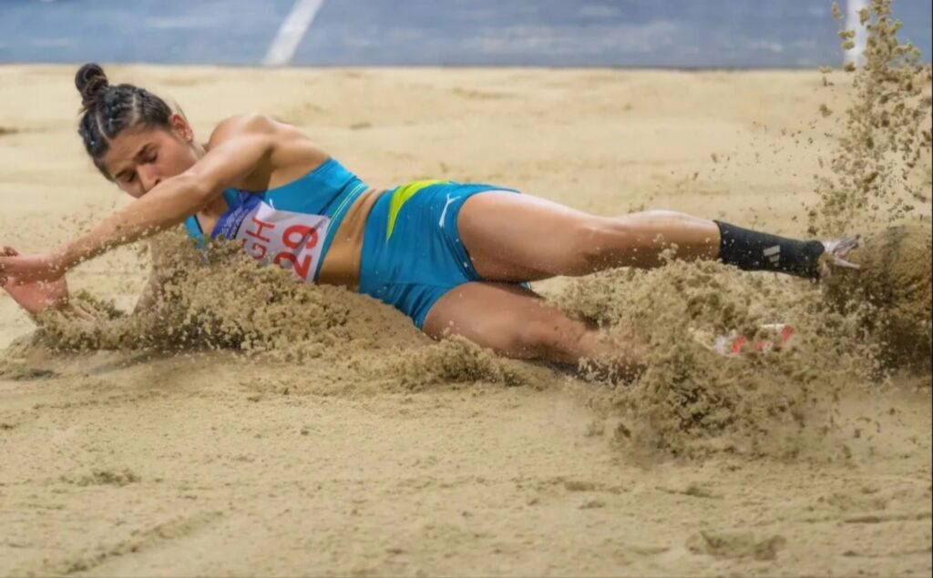 Shaili Singh making her landing during a long jump, focused and determined, captured in an event.
